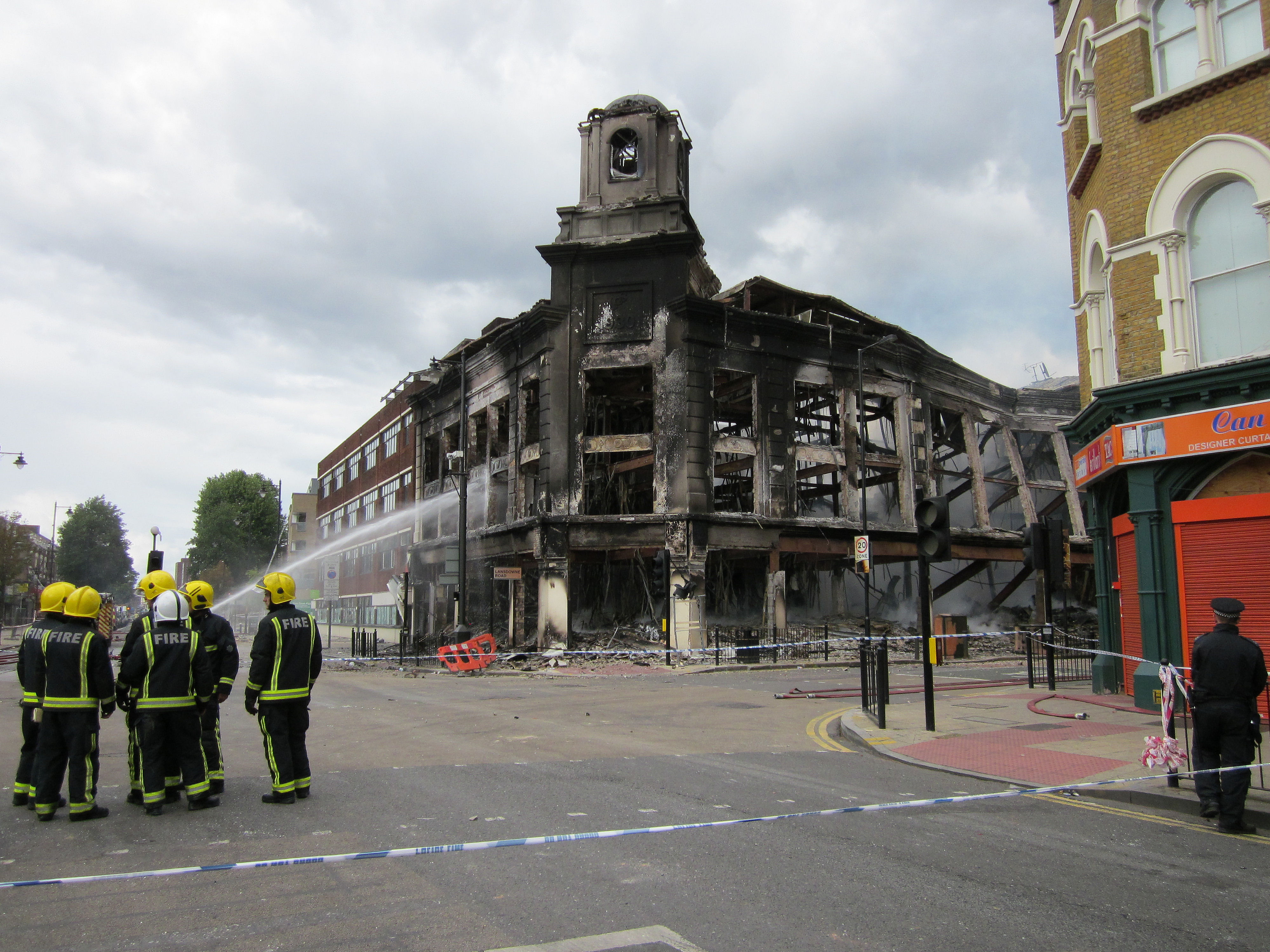 Firefighters douse a shop and flats destroyed by arson during the initial rioting in 2011 in Tottenham, London